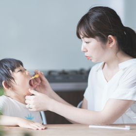 子供の口の中を見るお母さん