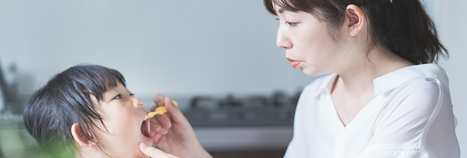 子供の口の中を見るお母さん